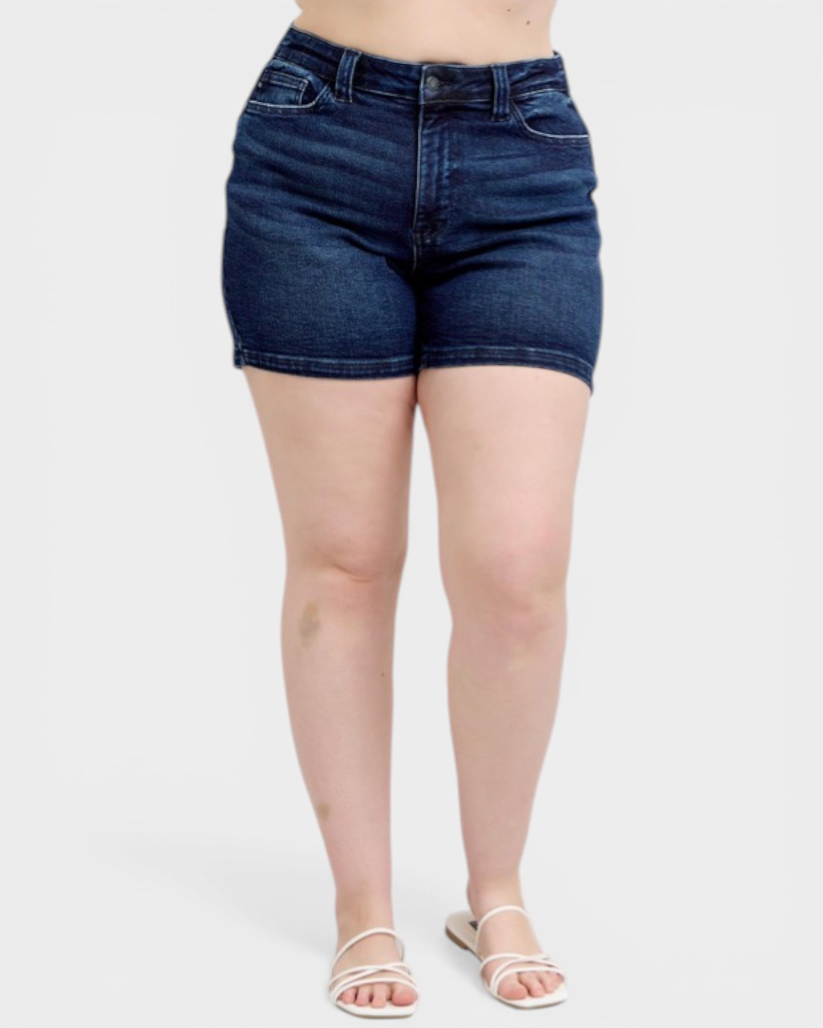 Person wearing dark blue denim shorts on a white background
