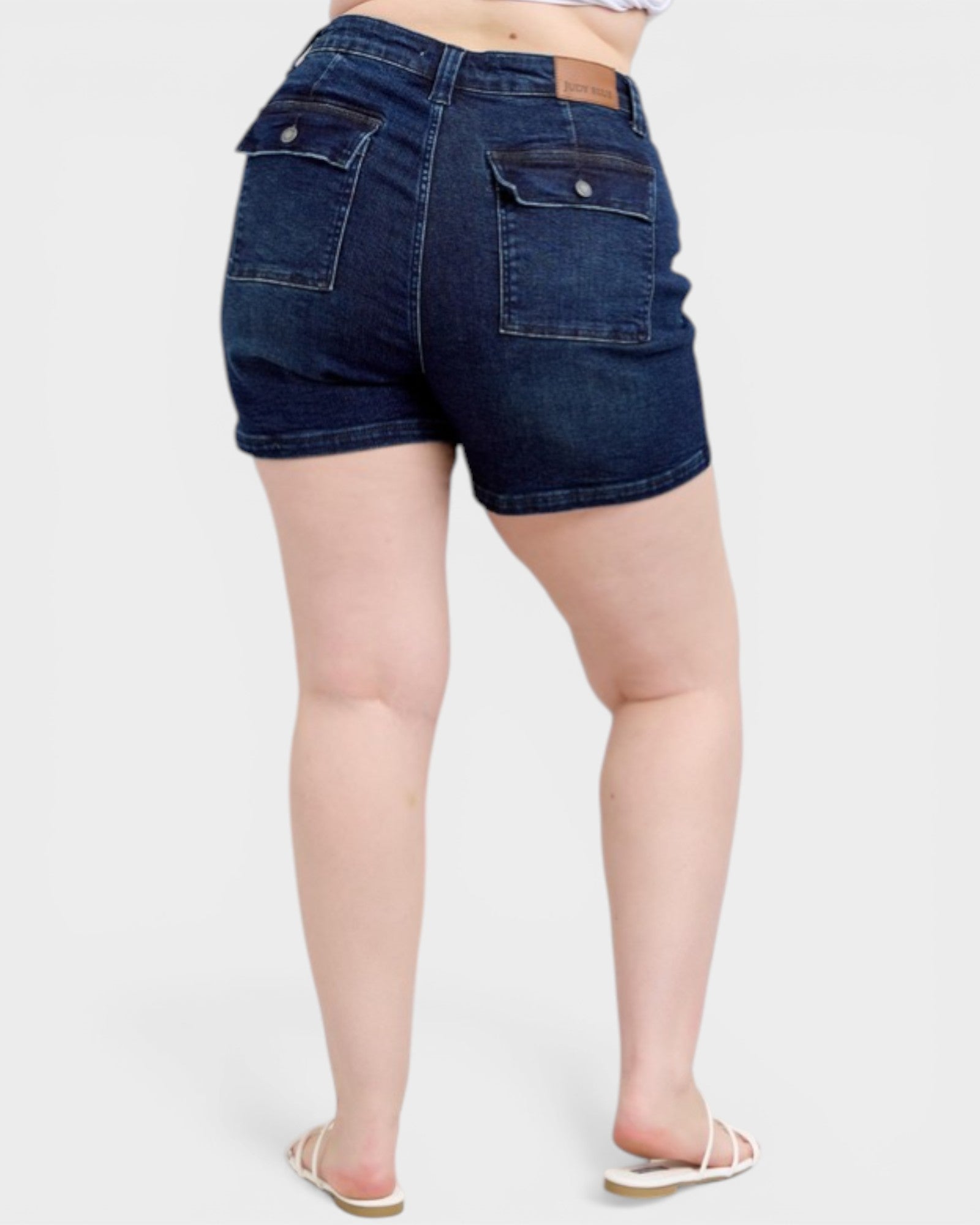Dark blue denim shorts worn by a person on a white background