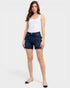 Woman wearing a white tank top and blue denim shorts on a white background
