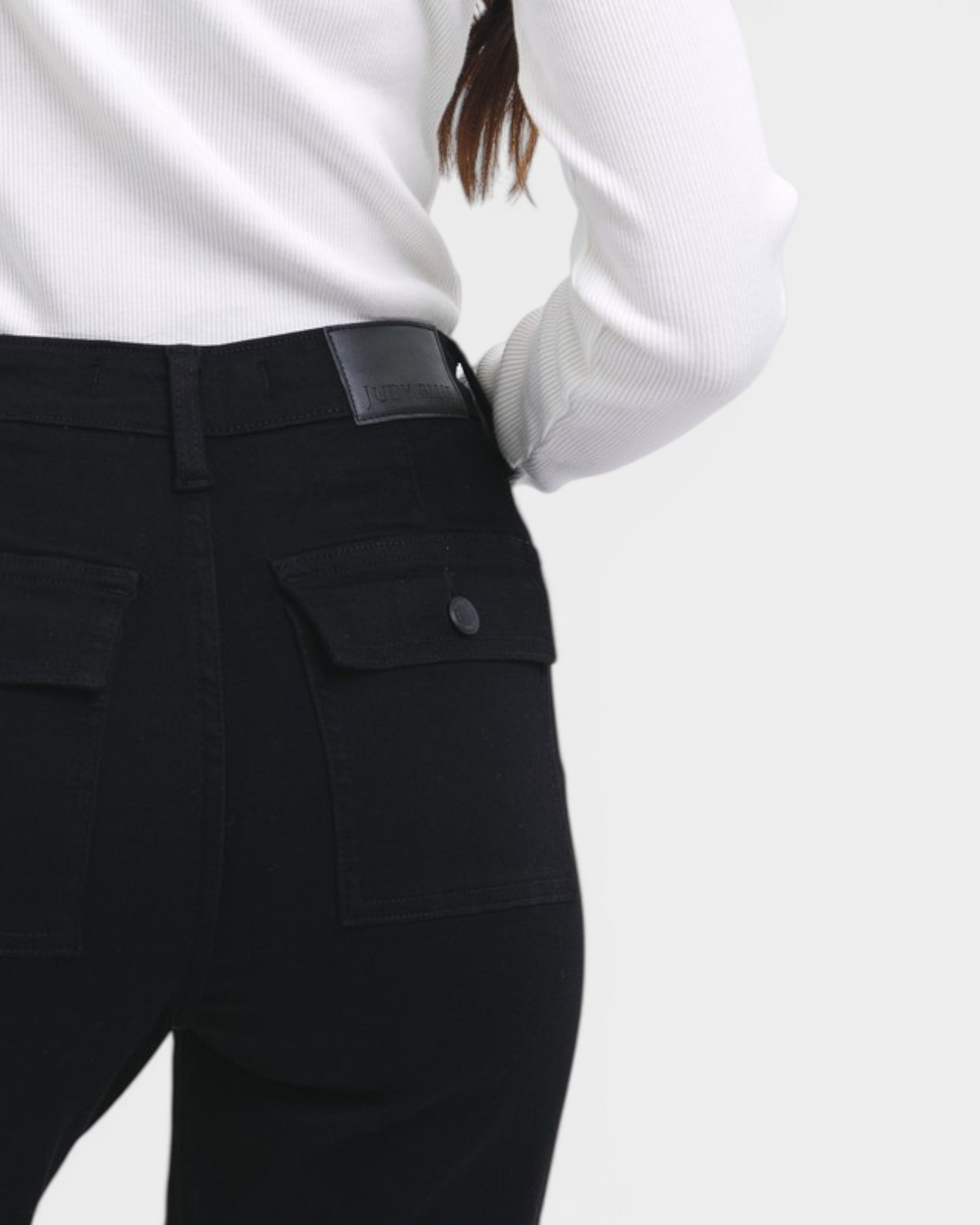 Person wearing black pants with a white shirt on a light gray background