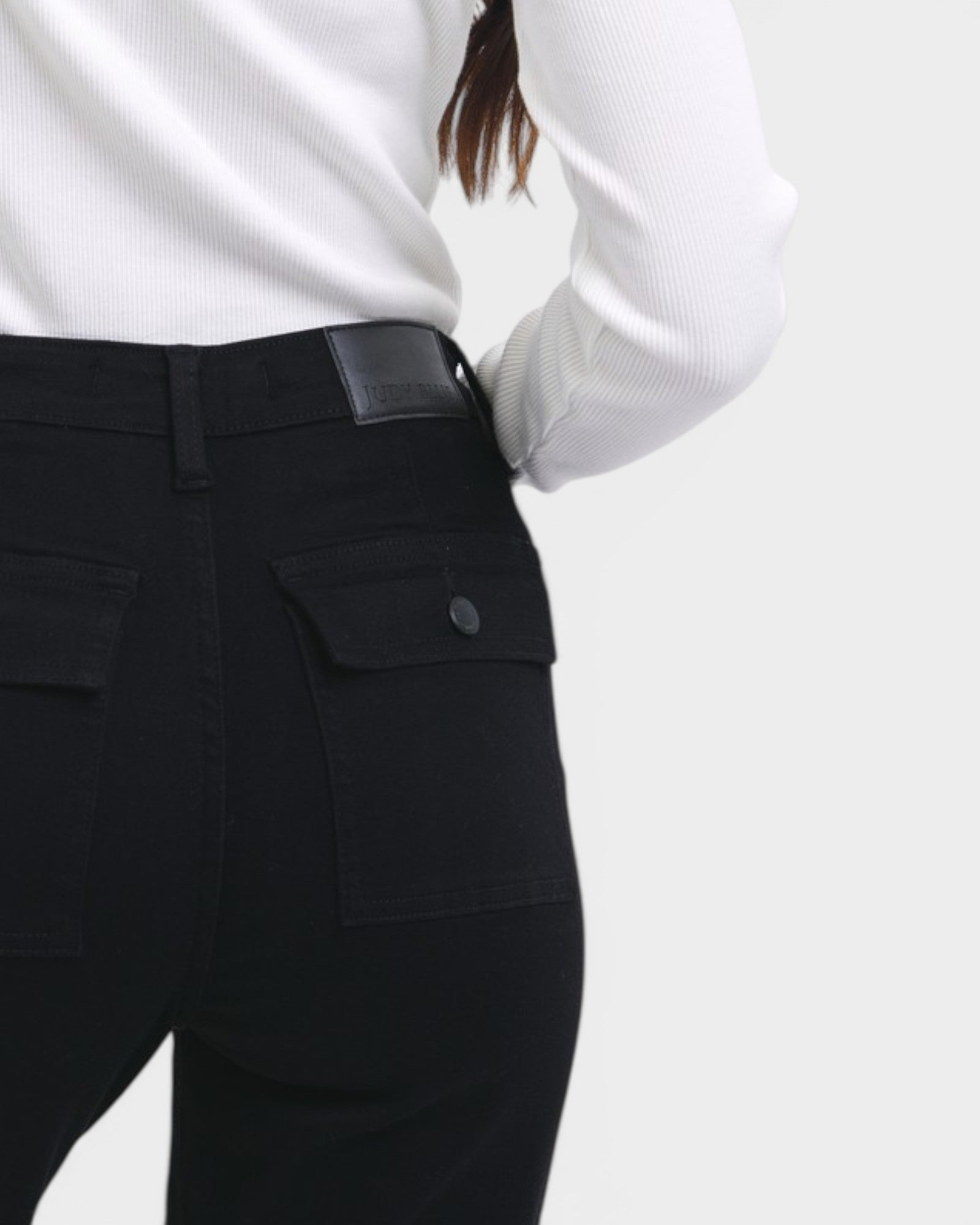 Person wearing black pants with a white shirt on a light gray background