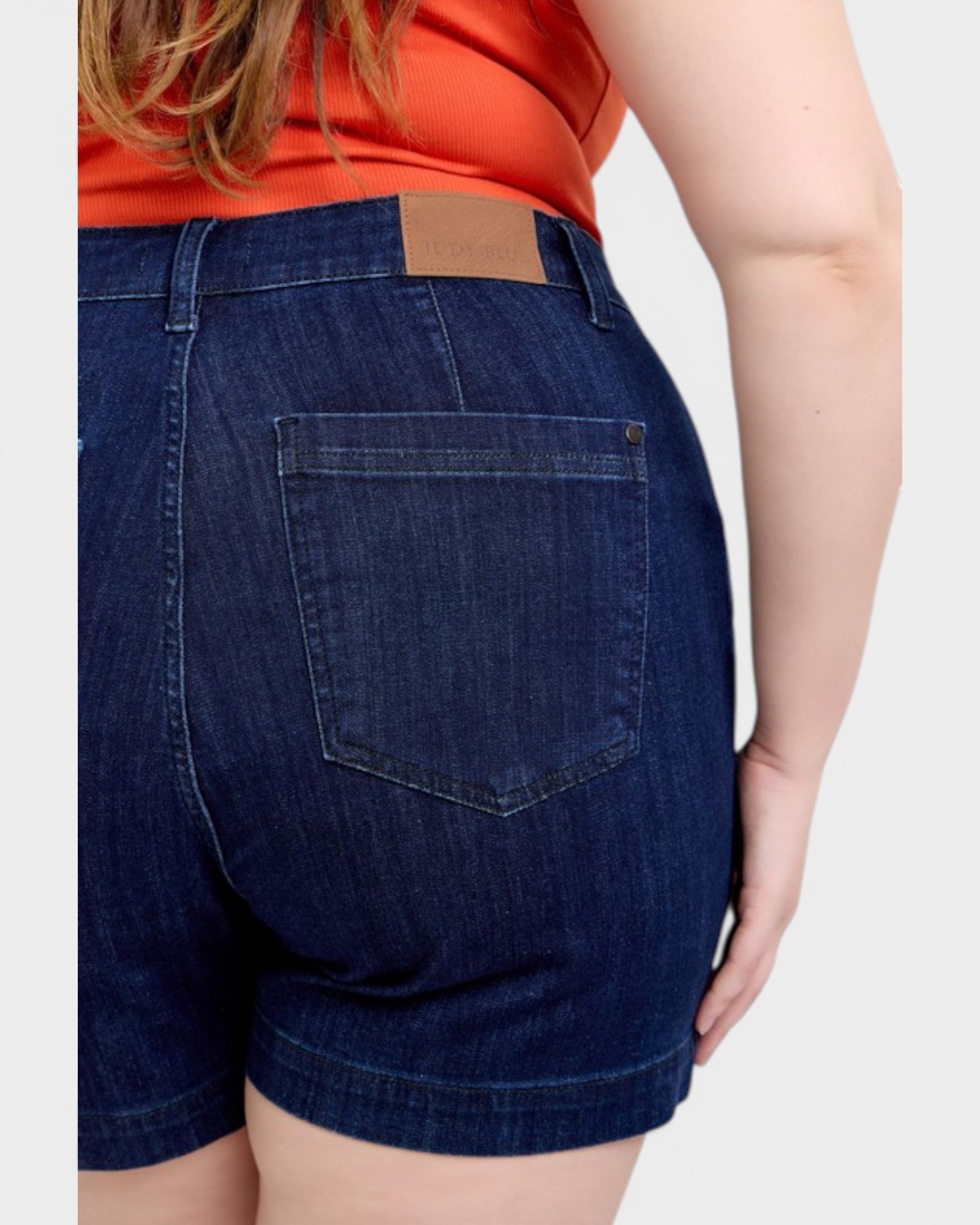 Person wearing blue denim shorts with a plain background