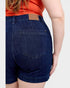 Person wearing blue denim shorts with a plain background