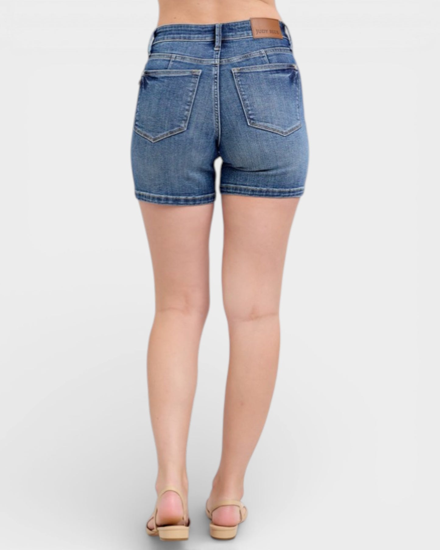 Blue denim shorts worn by a person on a white background