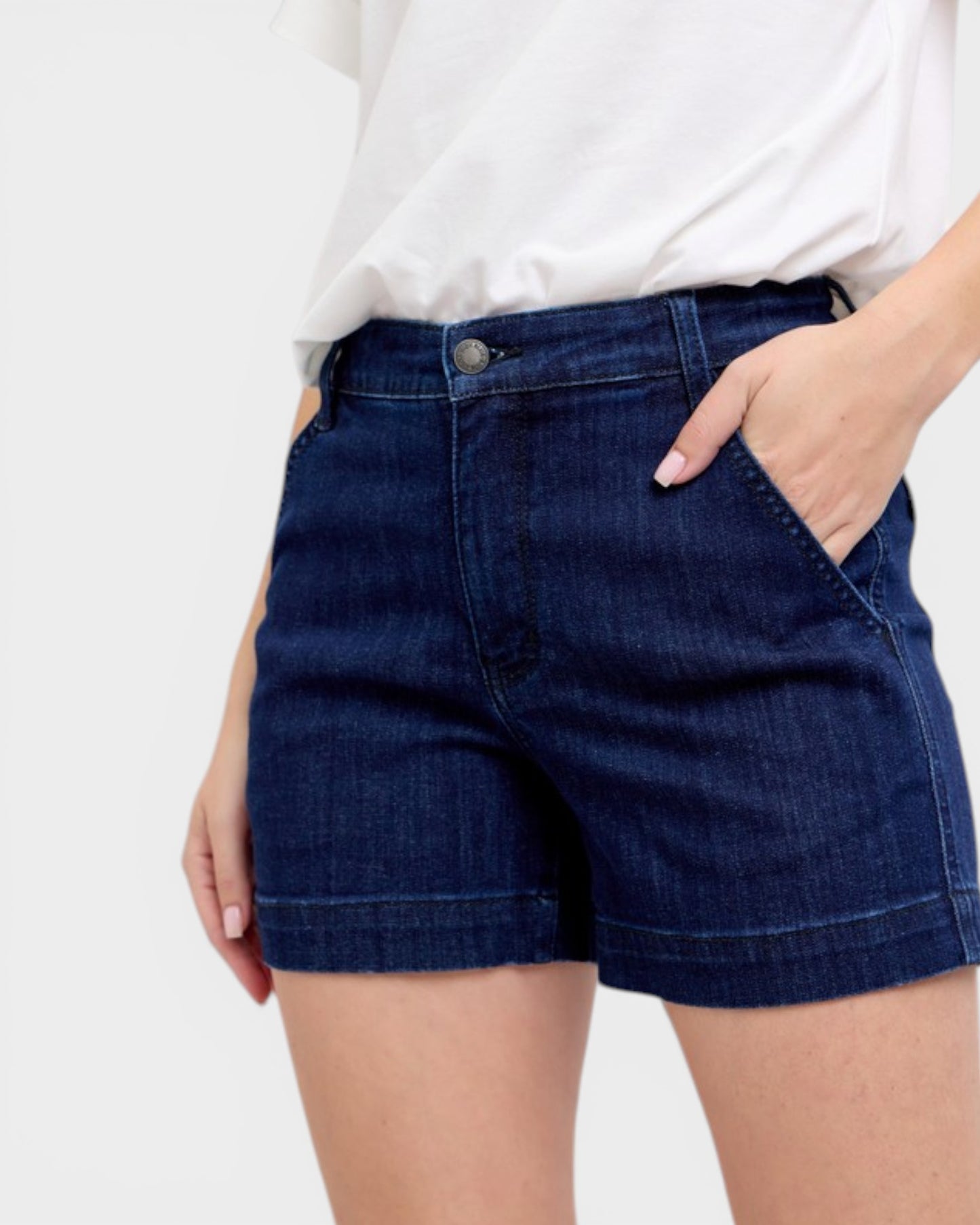 Person wearing dark blue denim shorts on a white background