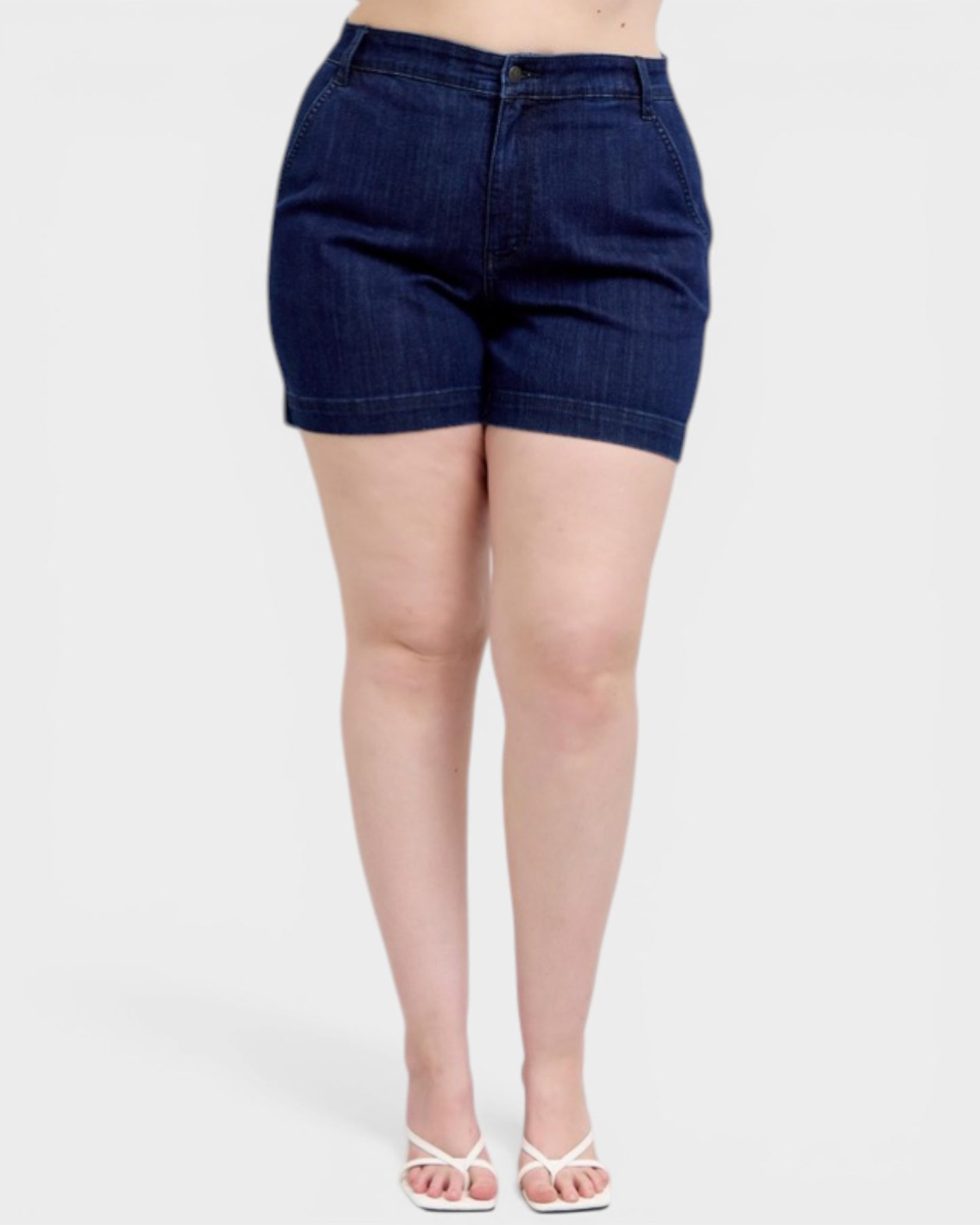 Person wearing dark blue denim shorts on a white background