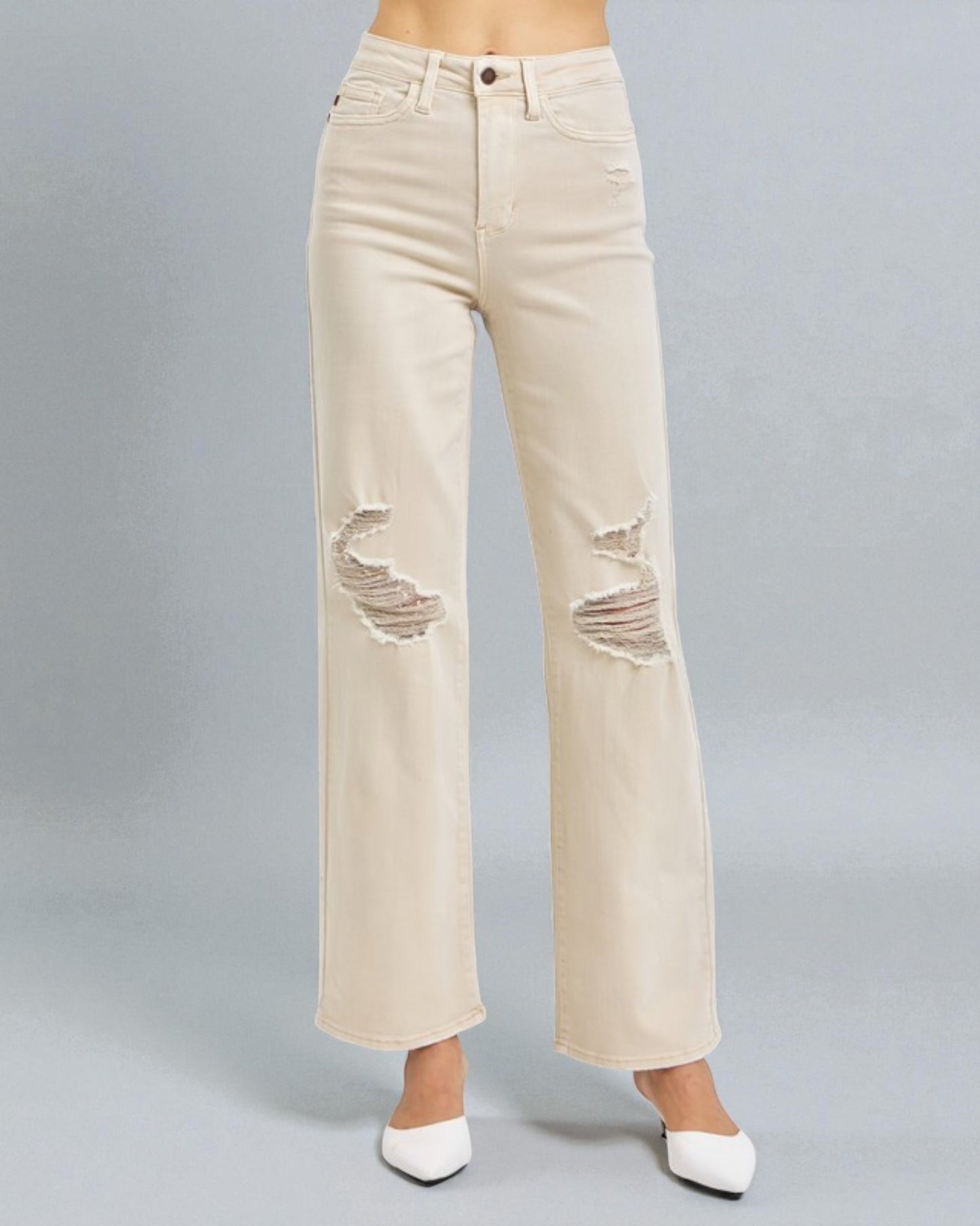 Beige distressed jeans on a gray background
