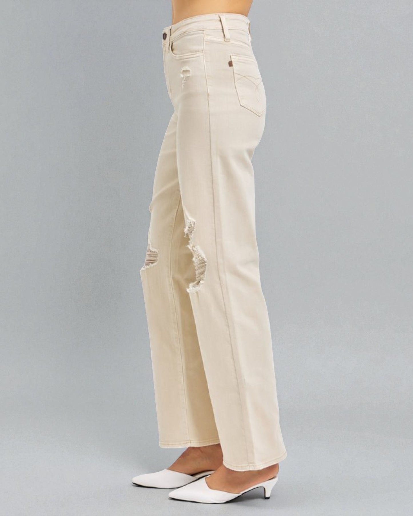 Beige wide-leg jeans worn by a person on a gray background