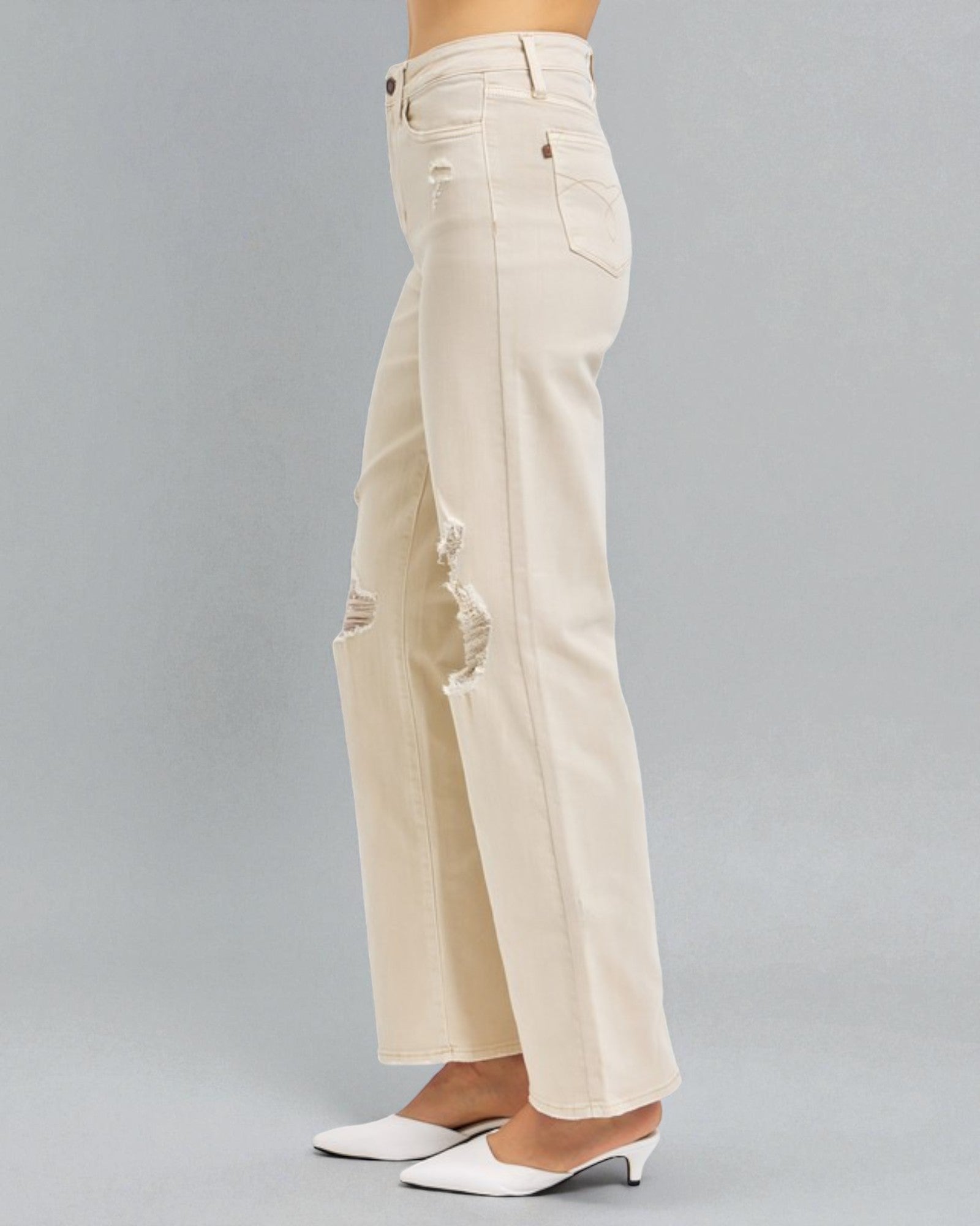 Beige wide-leg jeans worn by a person on a gray background