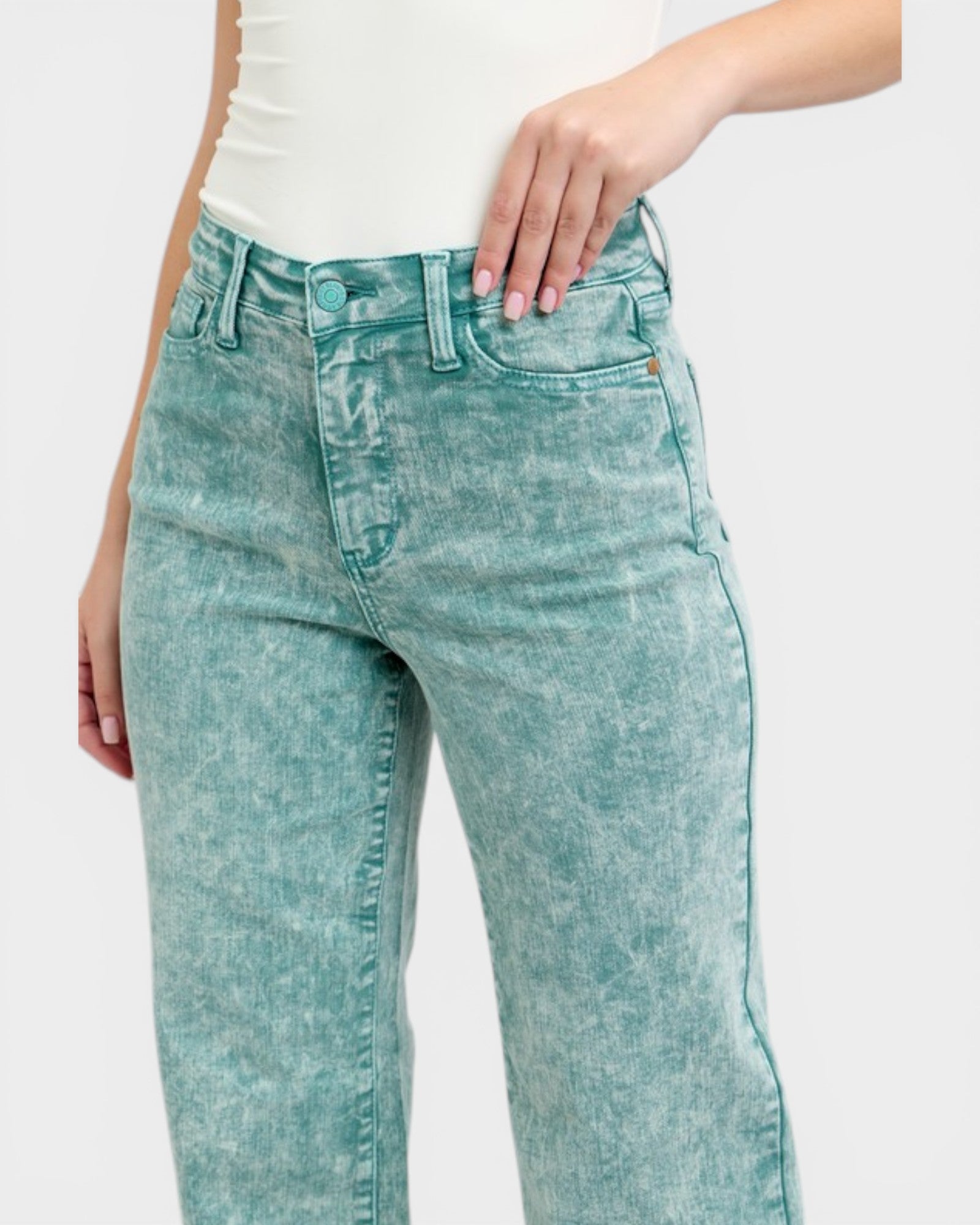 Teal acid-wash jeans worn by a person on a white background