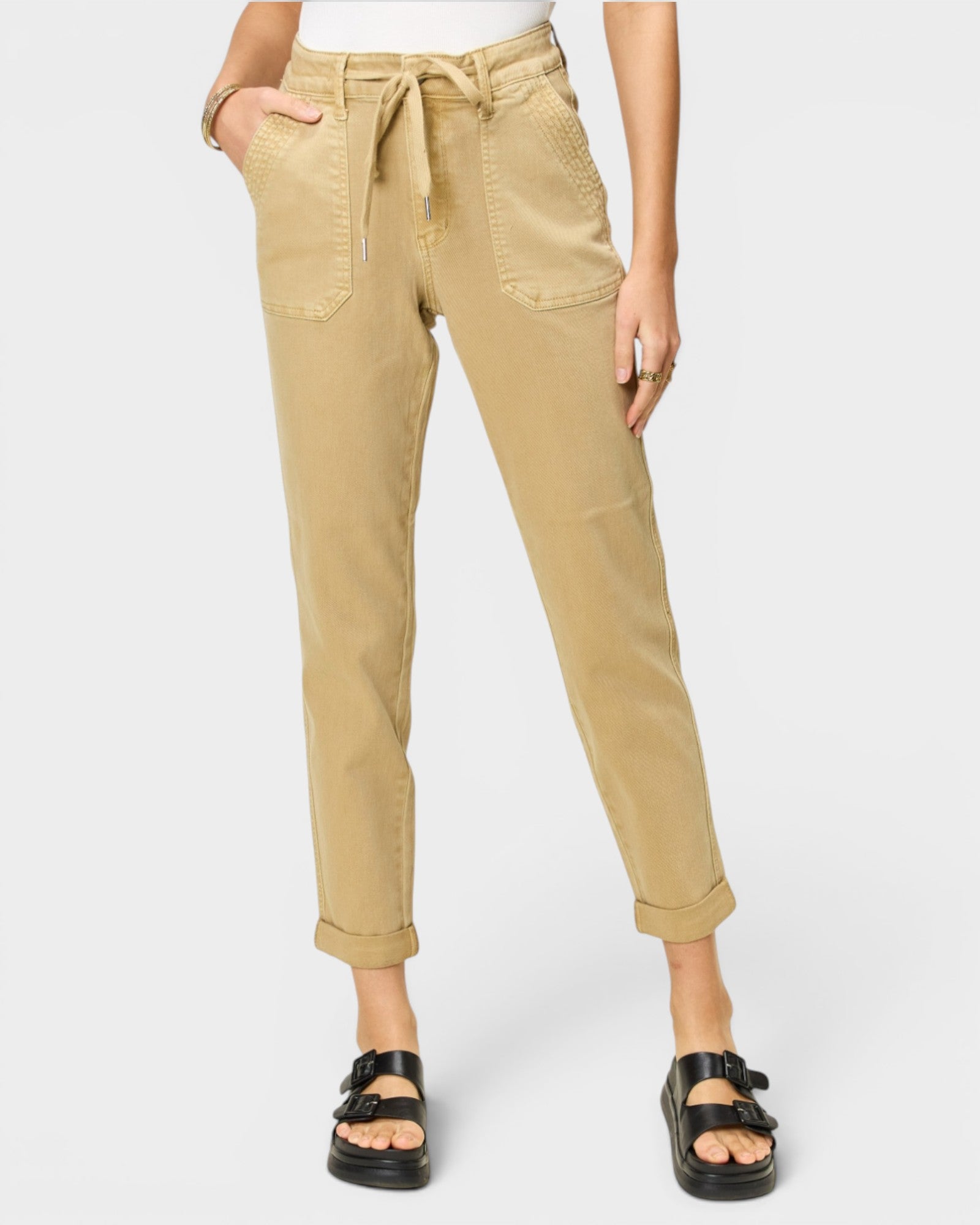 Person wearing beige pants with a white background