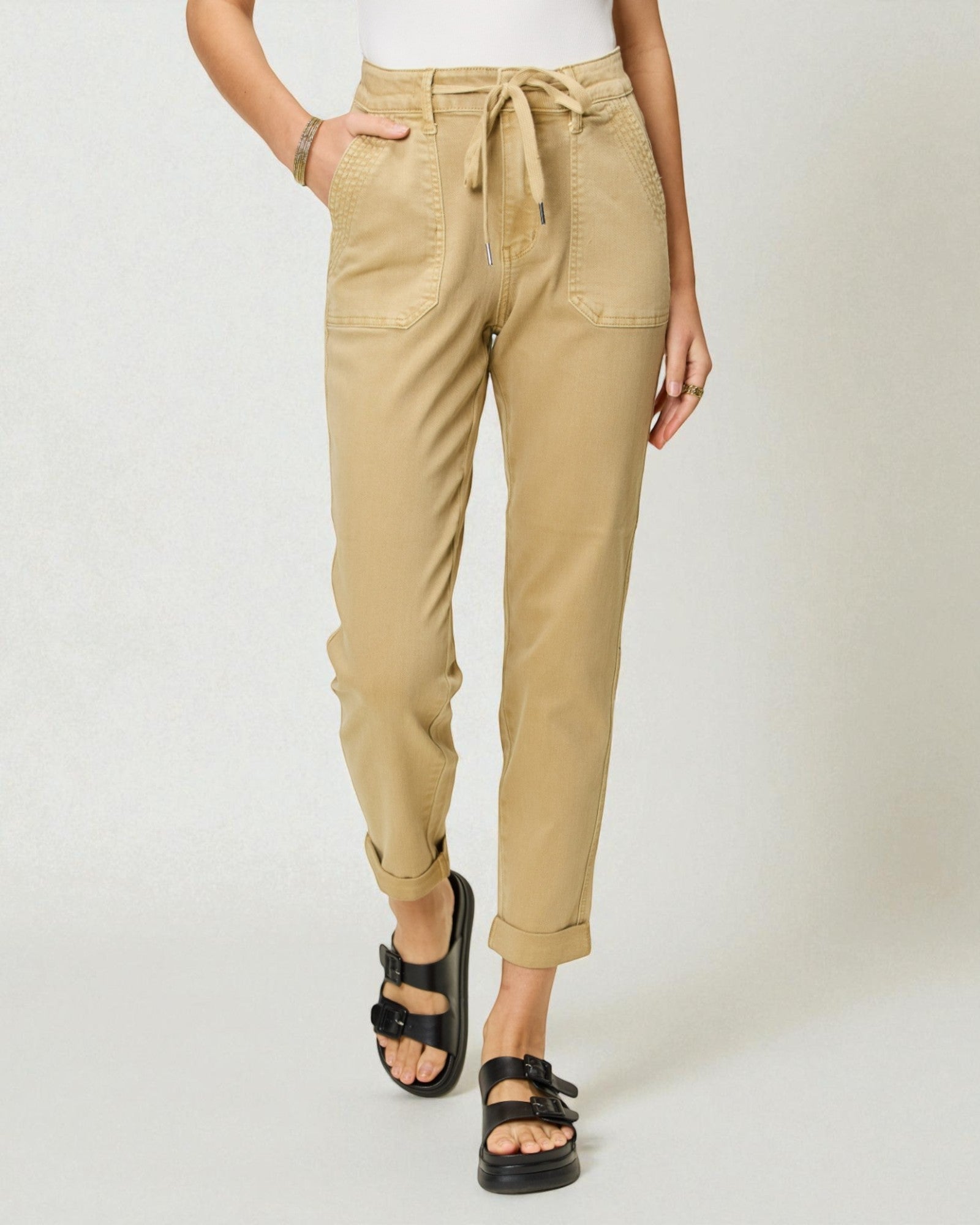 Person wearing beige pants with a white background