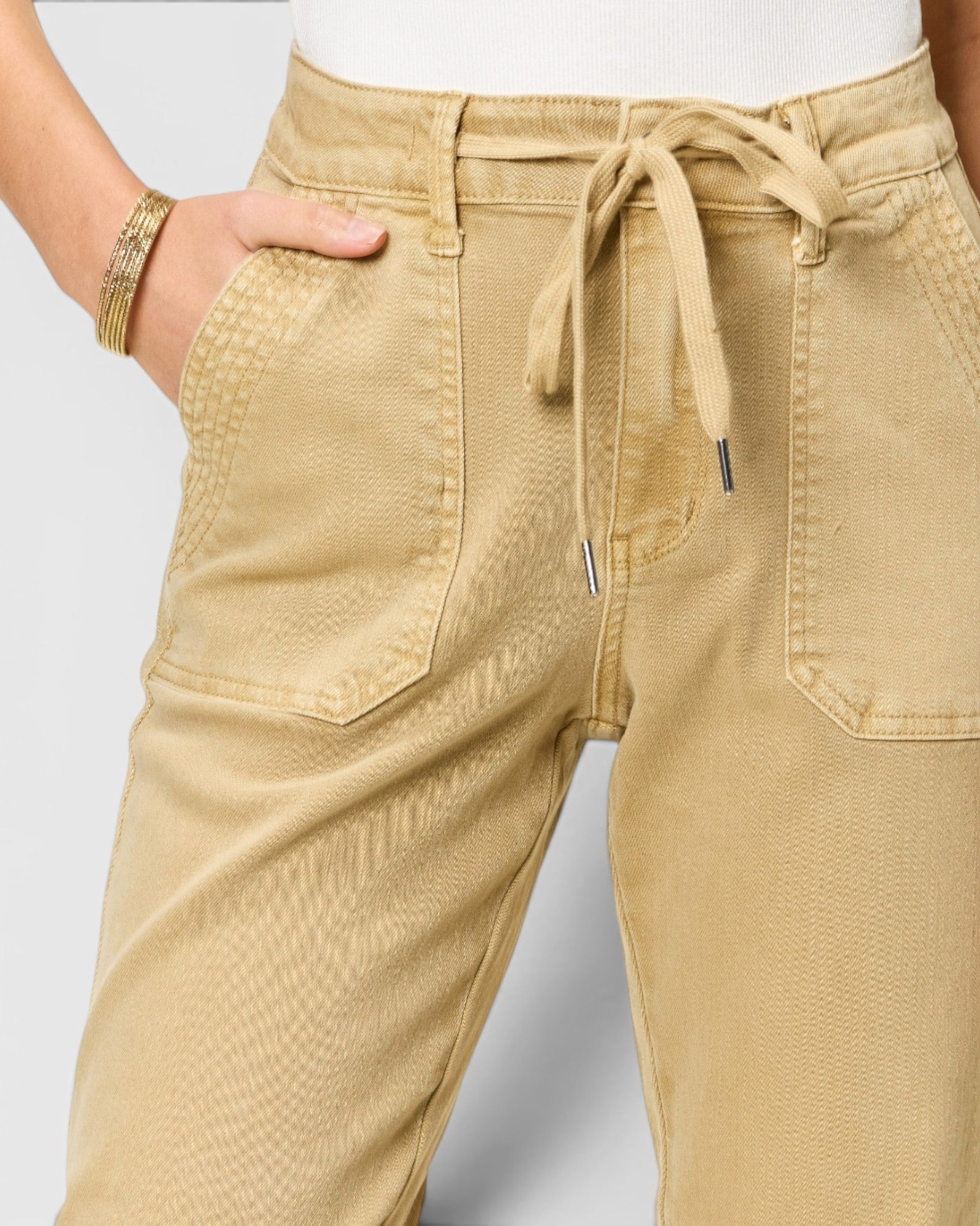 Beige pants with a drawstring waist on a plain background