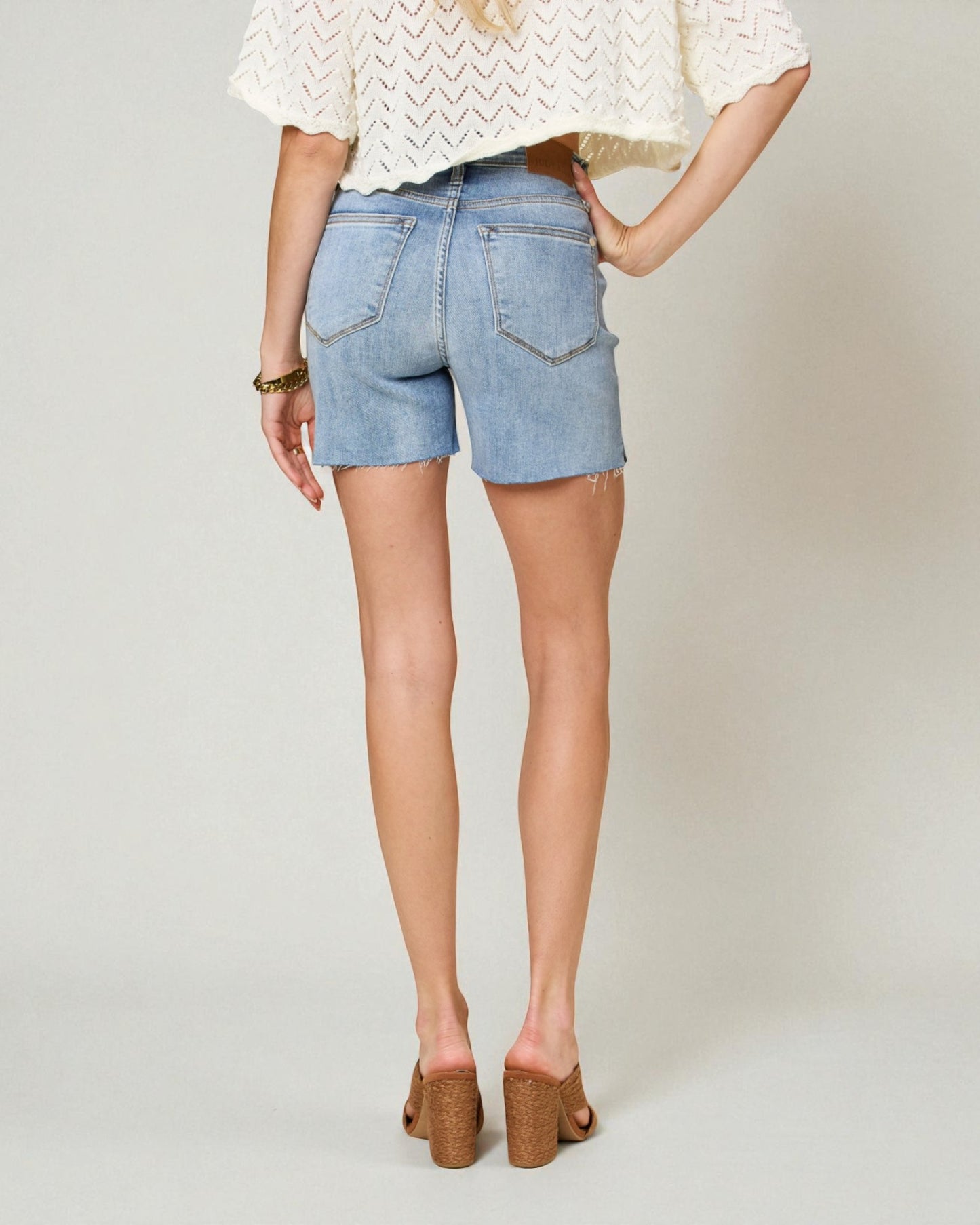 Person wearing light blue denim shorts on a plain background