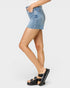 Person wearing a denim skirt and black sandals on a white background