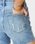 Close-up of a person wearing blue denim shorts with a decorative pocket.