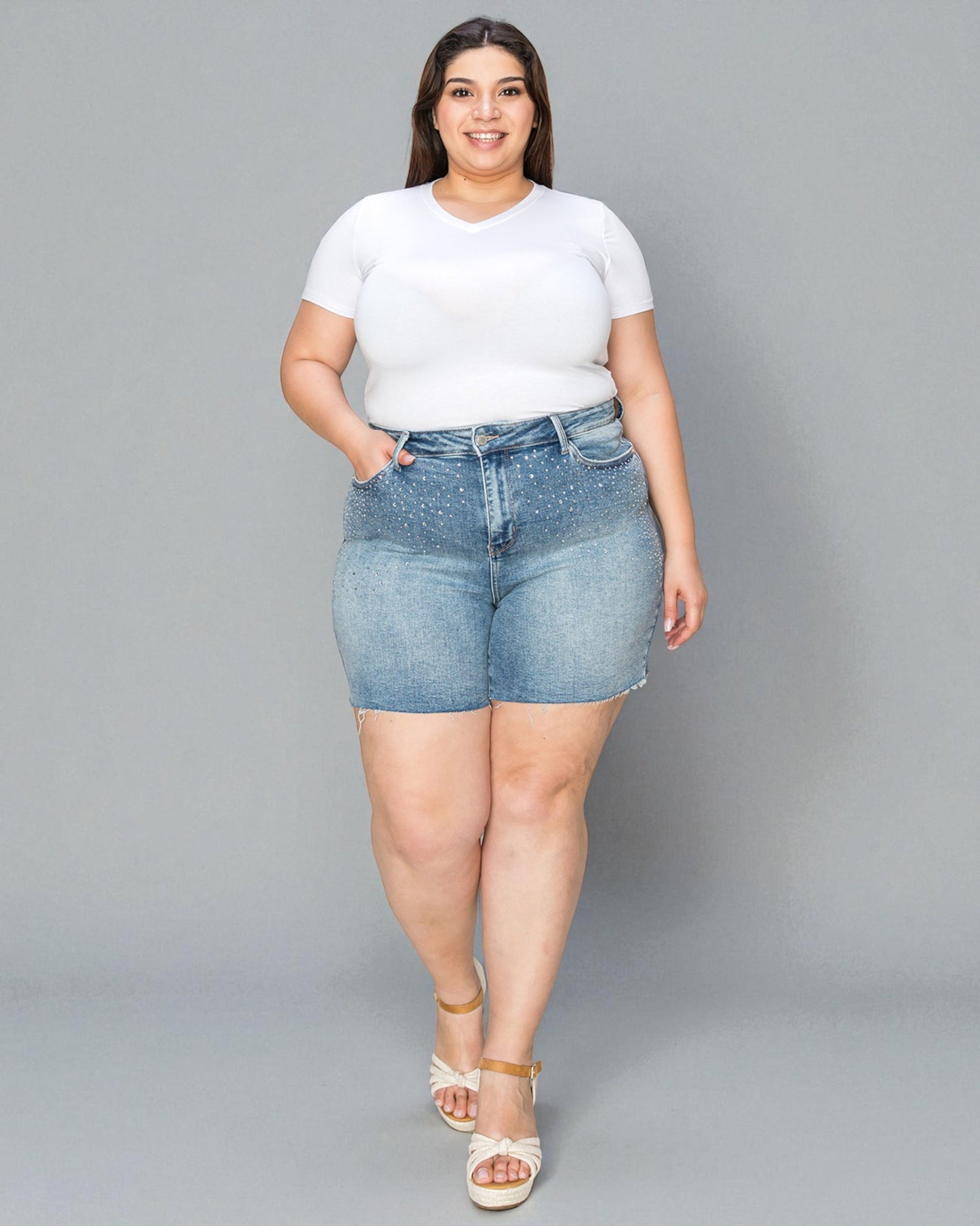 Woman wearing a white t-shirt and denim shorts on a gray background