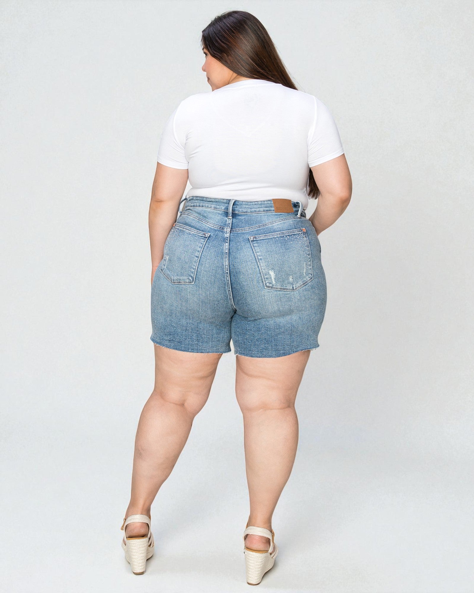 Person wearing light blue denim shorts and a white t-shirt on a plain background