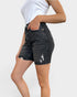 Person wearing black distressed denim shorts on a white background