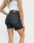 Person wearing black denim shorts on a plain background