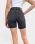 Person wearing black denim shorts on a plain background
