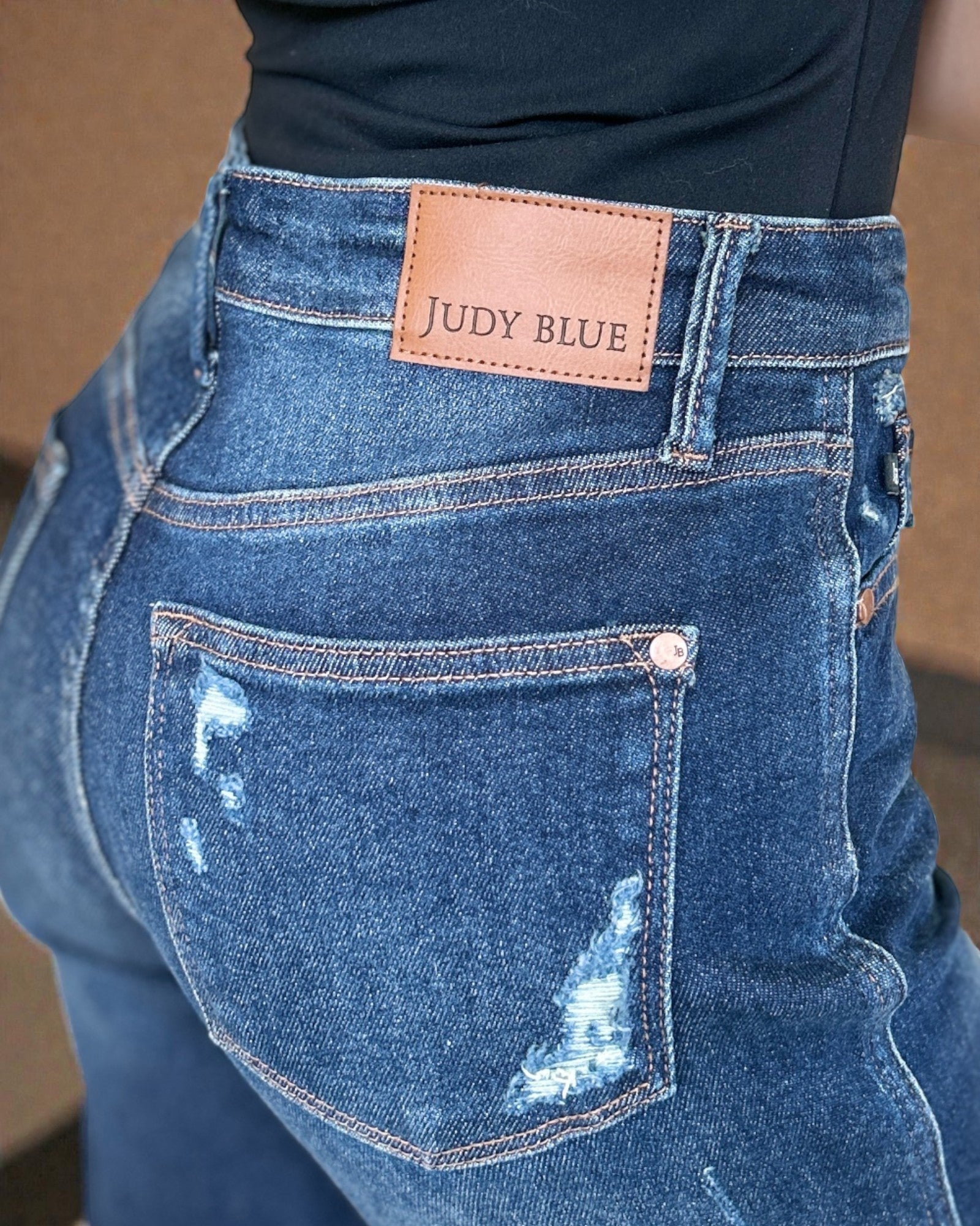 Close-up of blue jeans with a Judy Blue label on a brown background