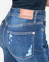 Close-up of the back waistband and pocket area of blue denim jeans with a tan leather patch reading 'JUDY BLUE' and visible distressing on the back pocket.