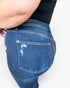 Close-up of a person wearing blue denim jeans, focusing on the back pocket and waist area against a plain light background.