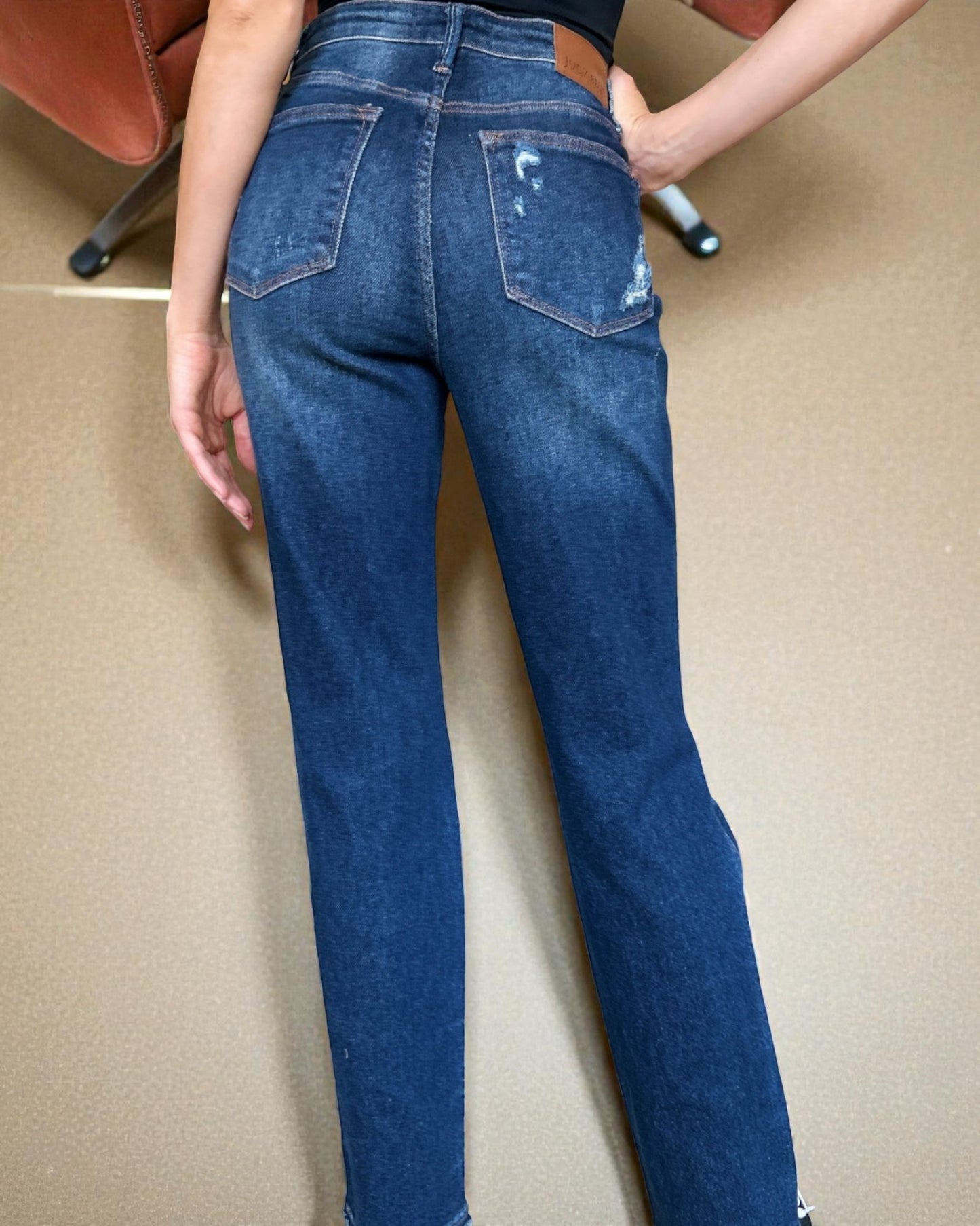 Person wearing blue jeans with a beige background