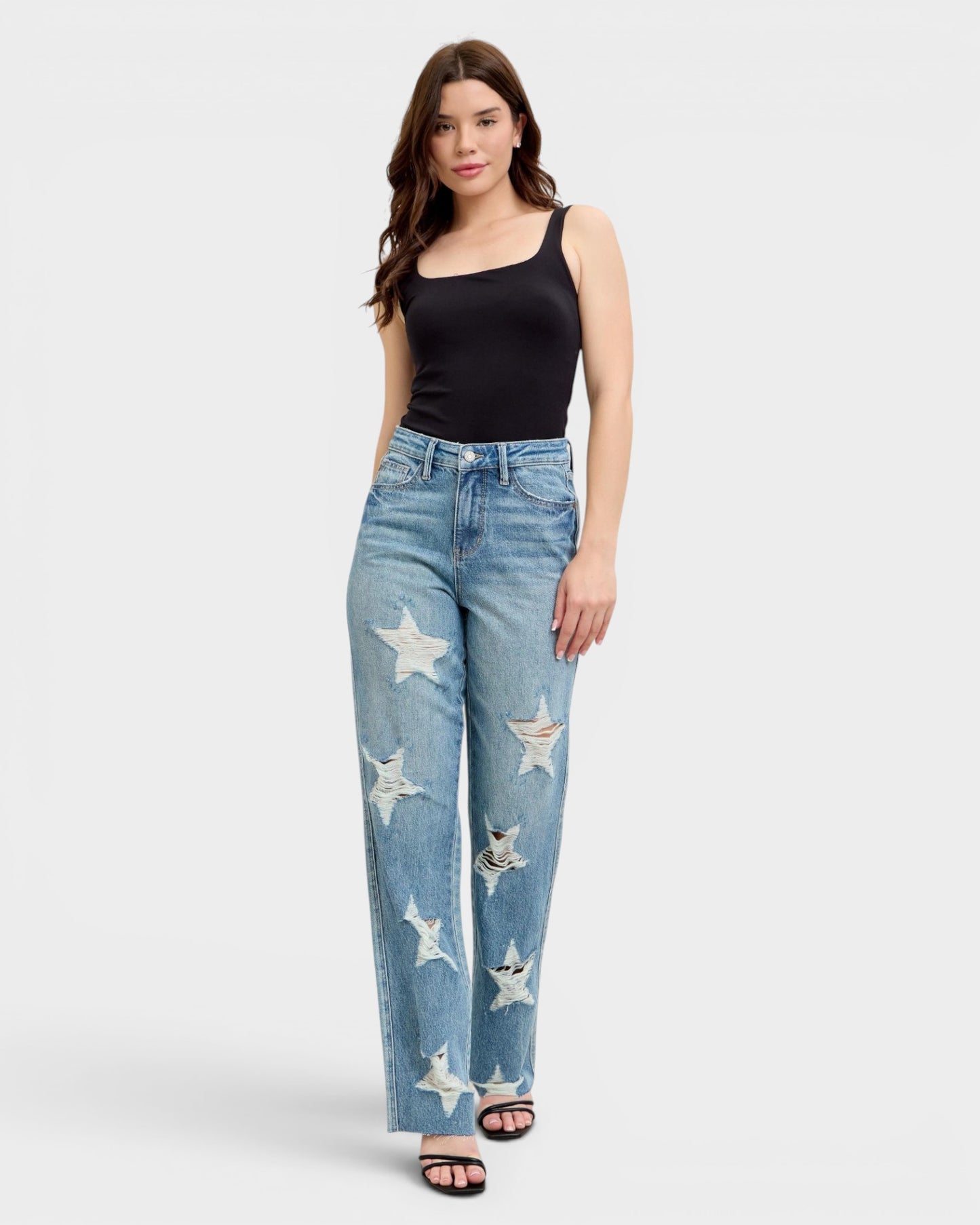 Woman wearing blue jeans with star distressing on a white background