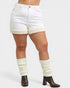 Person wearing white shorts with beige trim and brown boots on a white background
