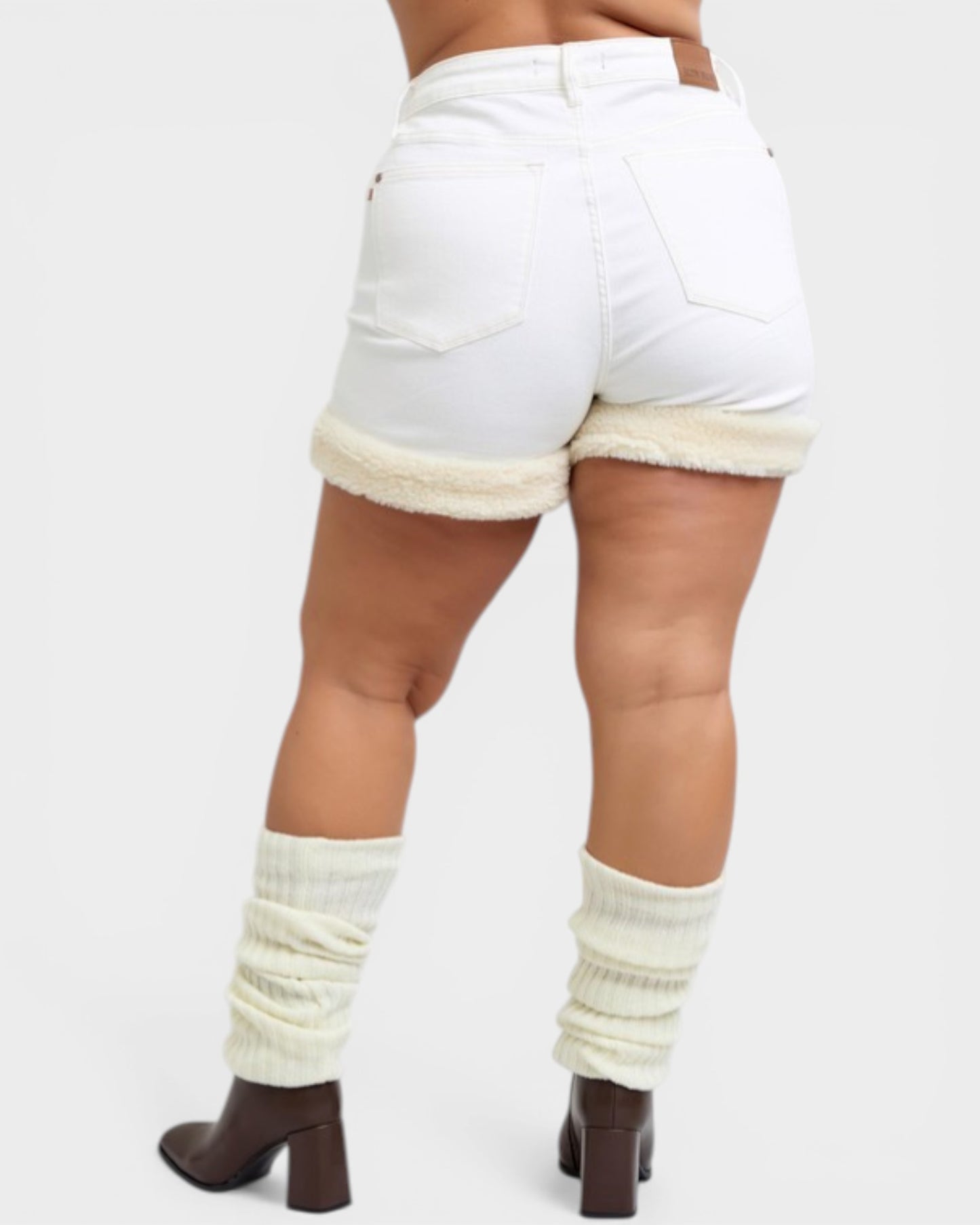 Person wearing white shorts with cream-colored trim and leg warmers on a plain background