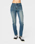 A person wearing medium-wash blue denim jeans and black low-top sneakers, shown from the waist down against a light gray studio background.