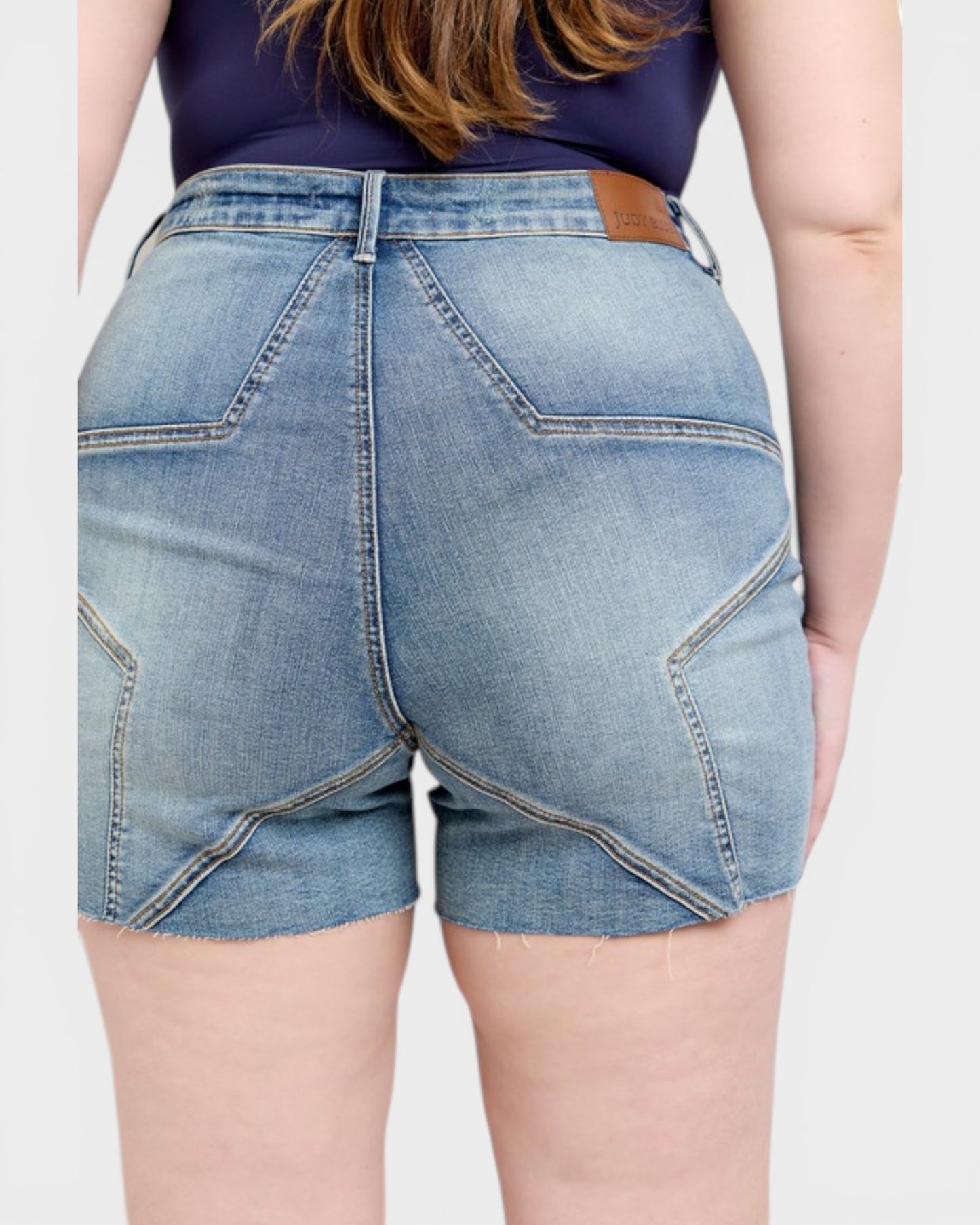 Person wearing blue denim shorts on a plain background