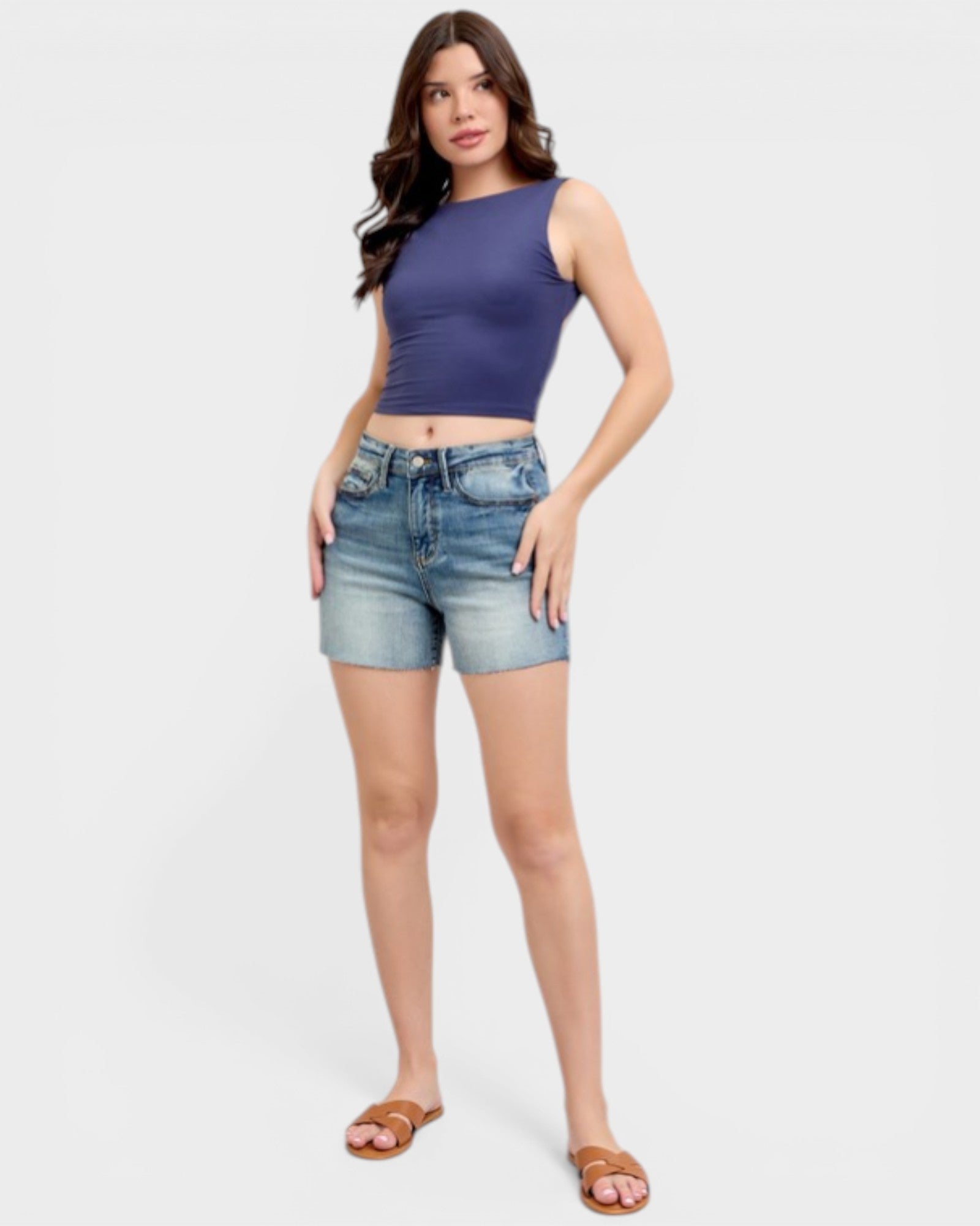 Woman wearing a blue crop top and denim shorts on a white background