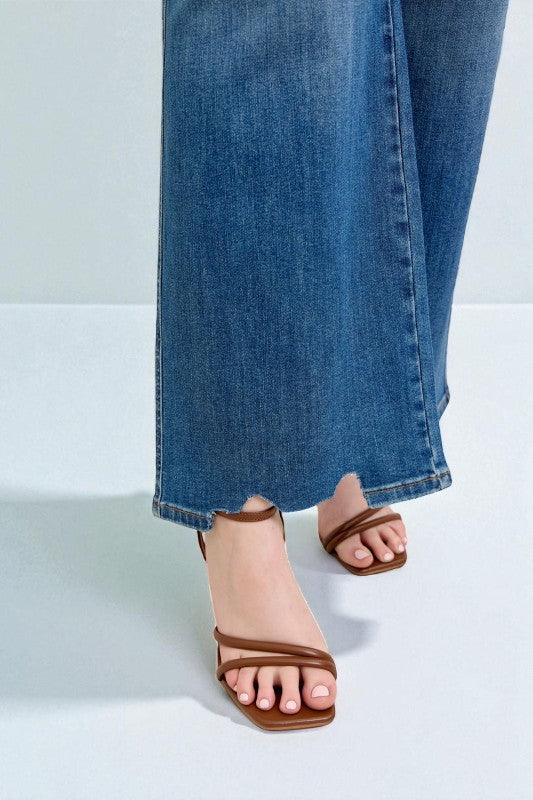 Brown sandals worn with blue jeans on a white background