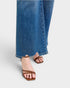 Blue jeans and brown sandals on a light gray background