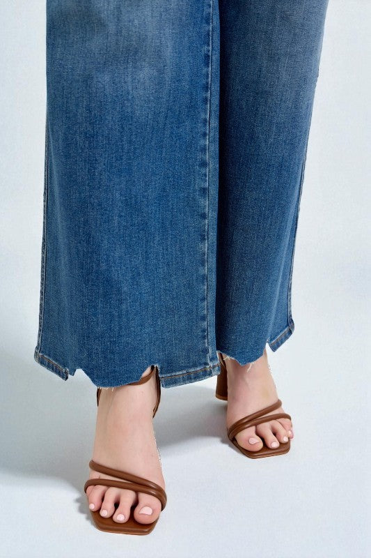 Brown sandals worn with blue jeans on a white background