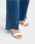Close-up of blue jeans and white sandals on a light gray background