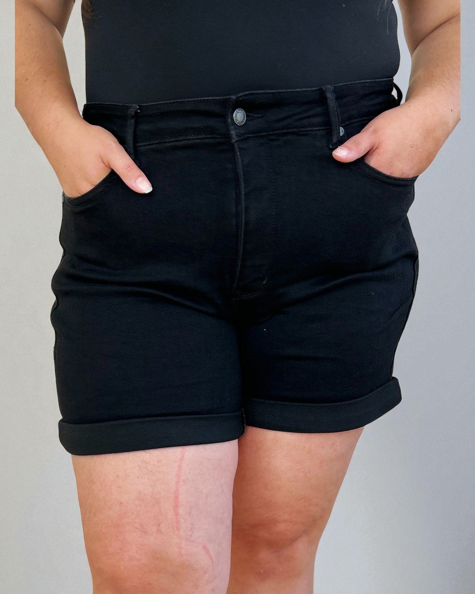 Person wearing black shorts with a plain background