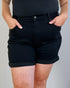 Person wearing black shorts with a plain background