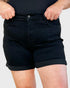 Person wearing black denim shorts on a plain background