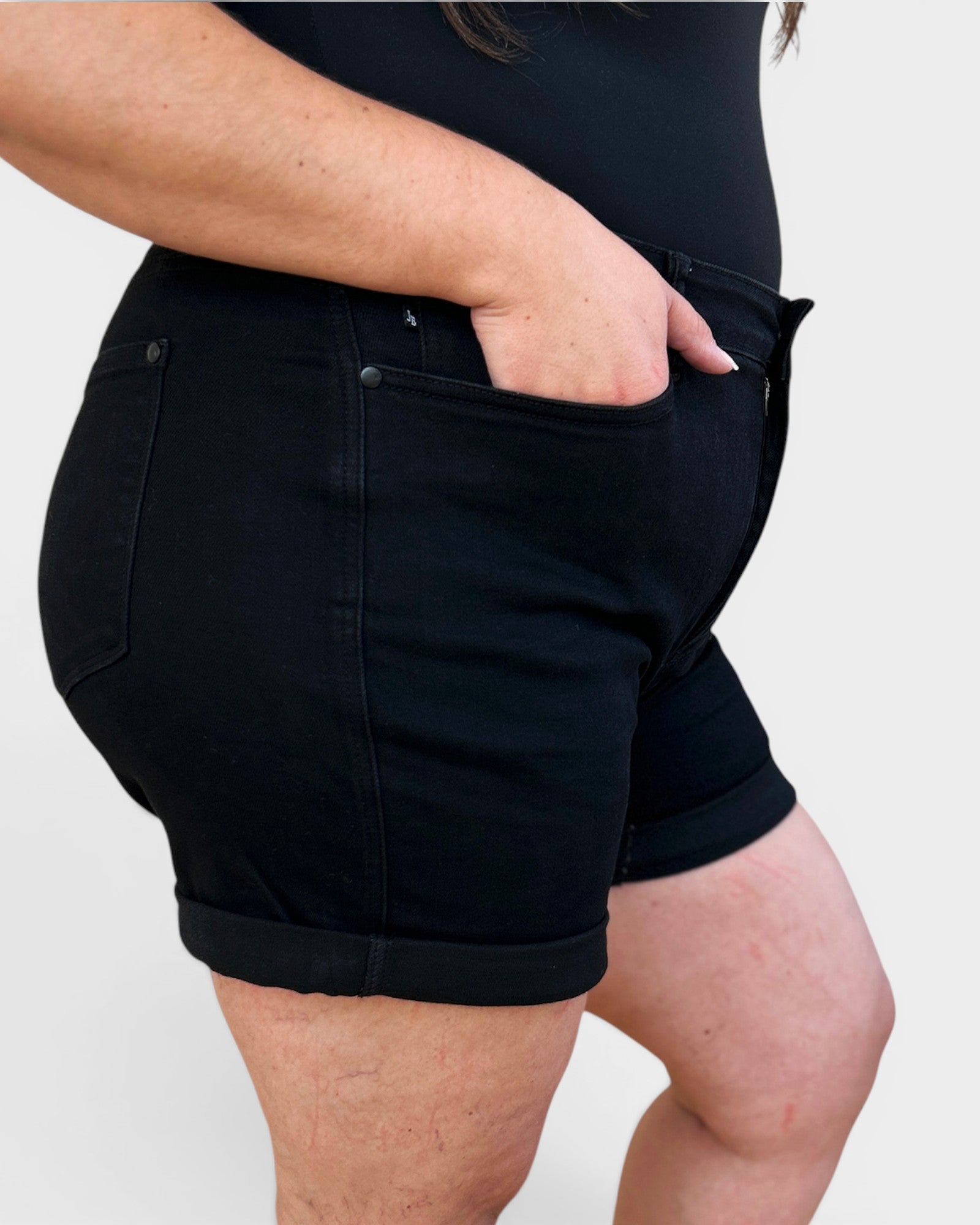 Person wearing black shorts on a plain background