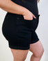Person wearing black shorts on a plain background