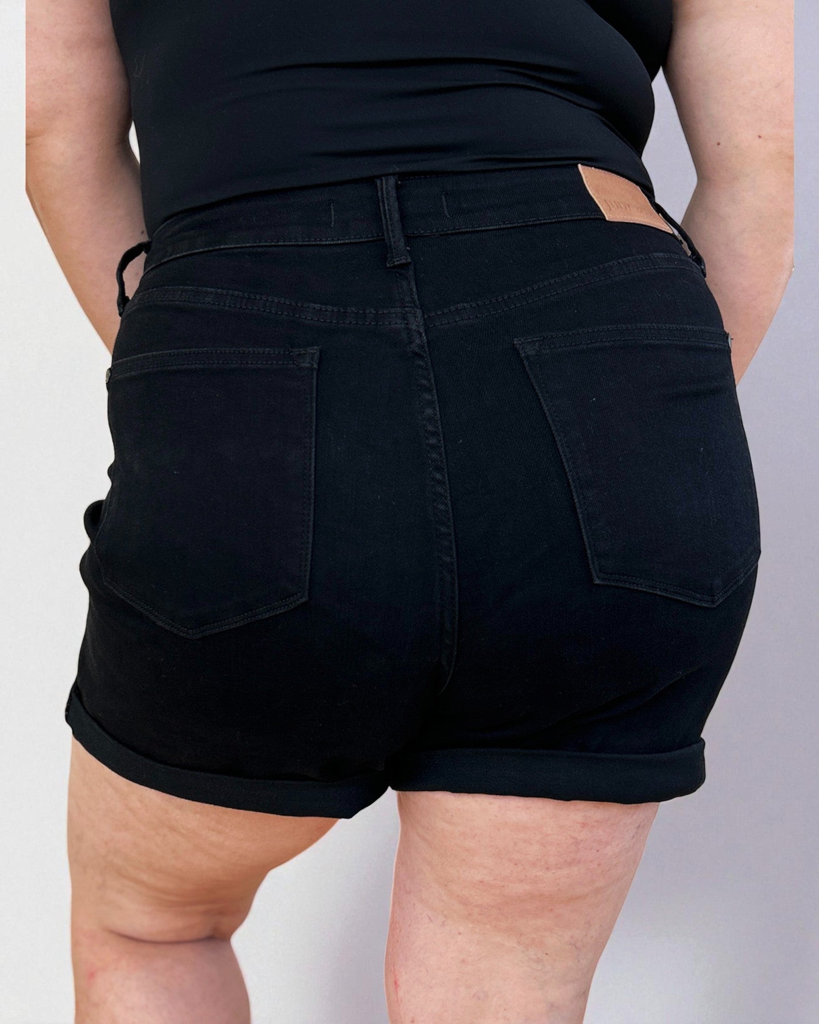 Person wearing black shorts on a plain background