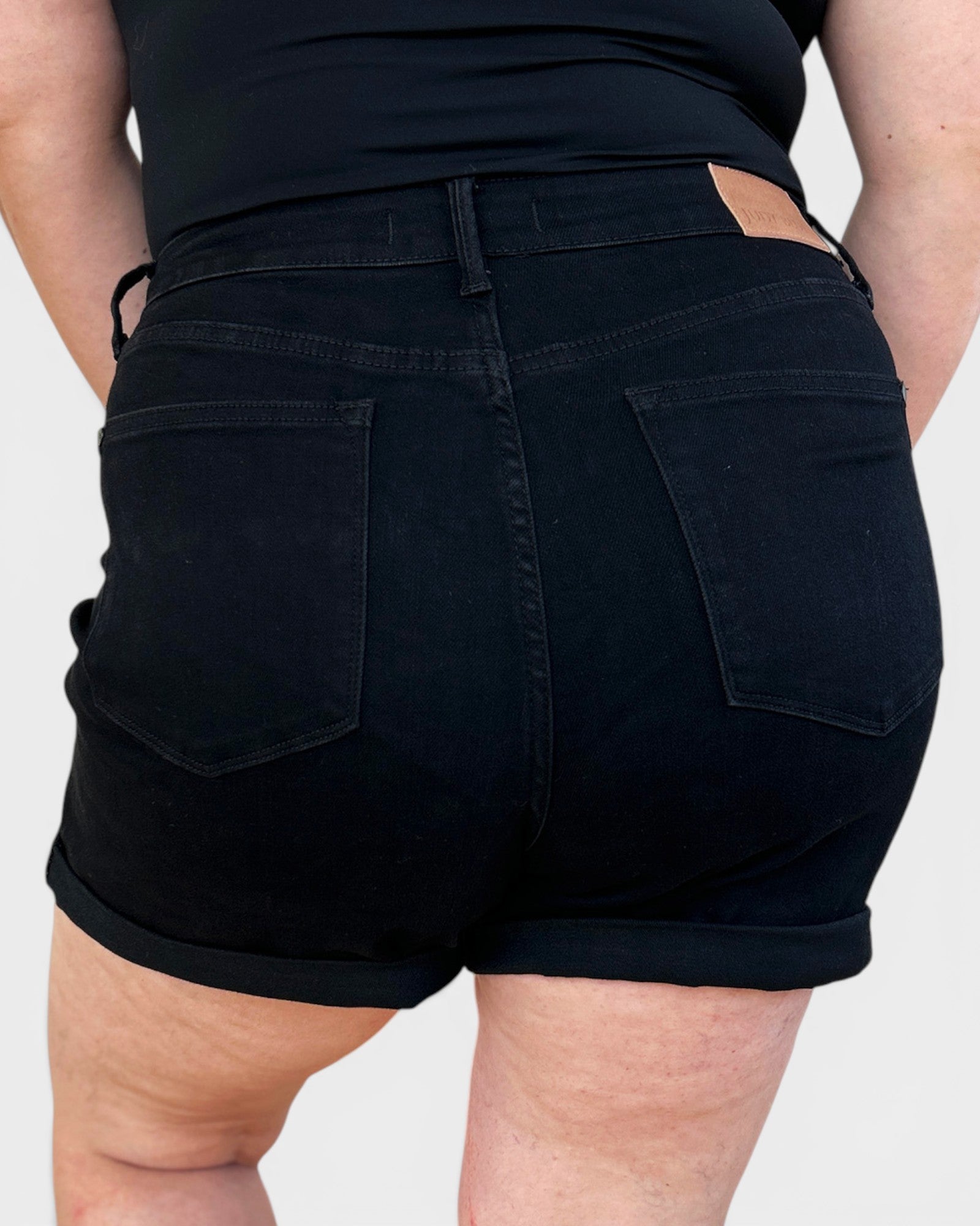 Person wearing black shorts on a plain background