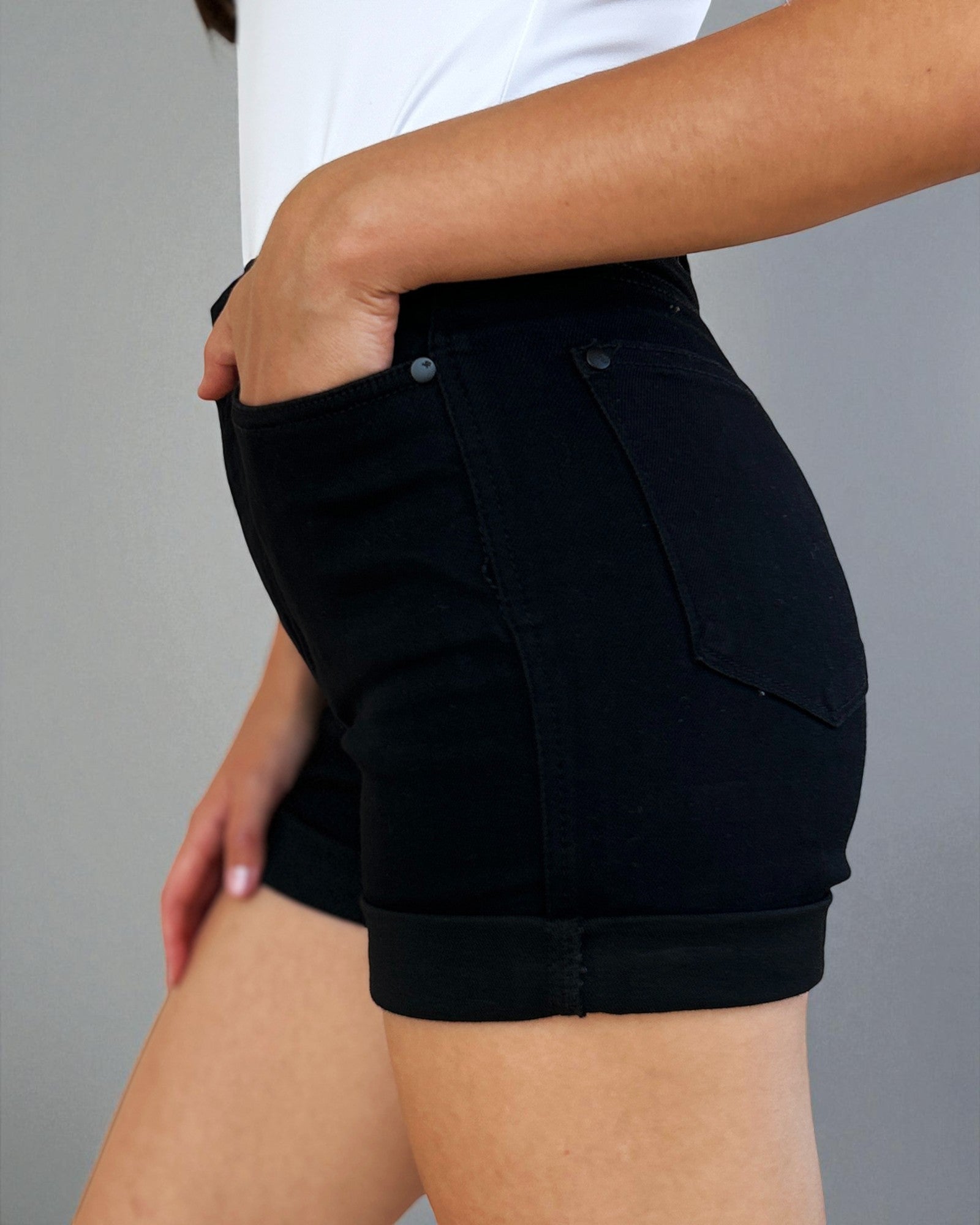 Person wearing black shorts with a gray background
