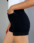 Person wearing black shorts with a gray background