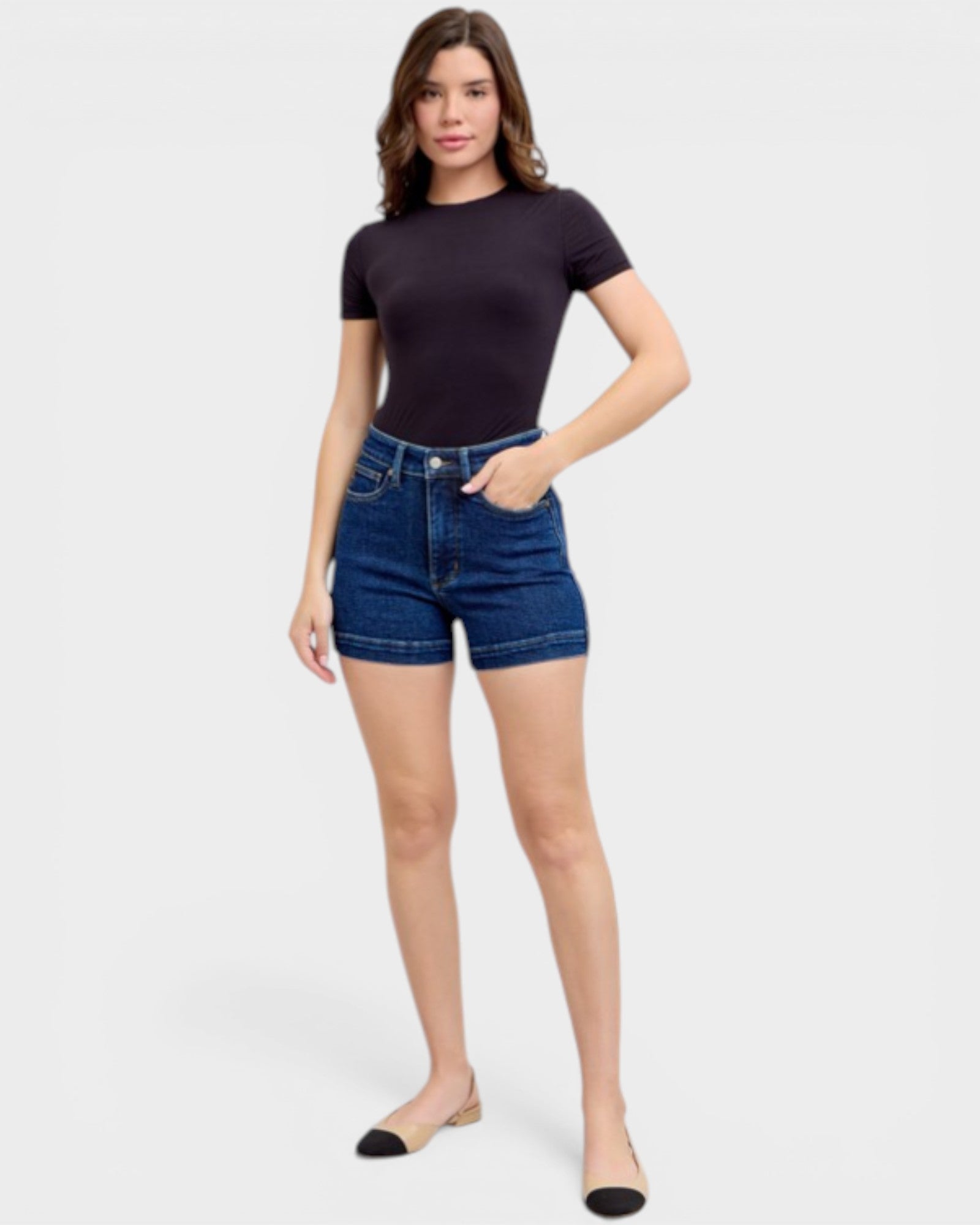 Woman wearing a black t-shirt and blue denim shorts on a white background