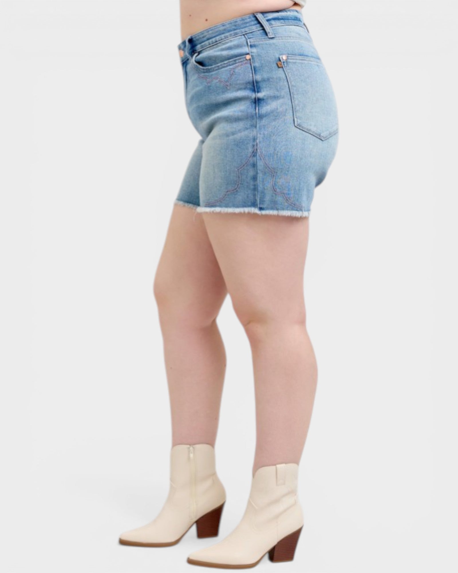 Person wearing light blue denim shorts and white boots on a plain background